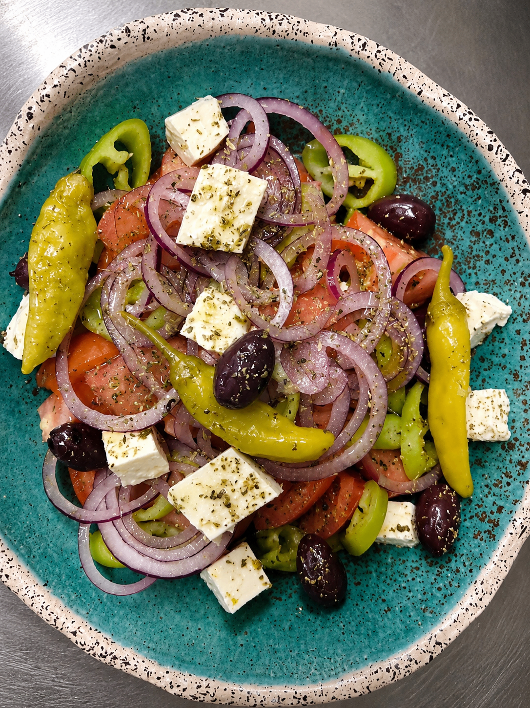 Griechischer Bauernsalat mit Feta, roten Zwiebeln, Oliven und Peperoni.