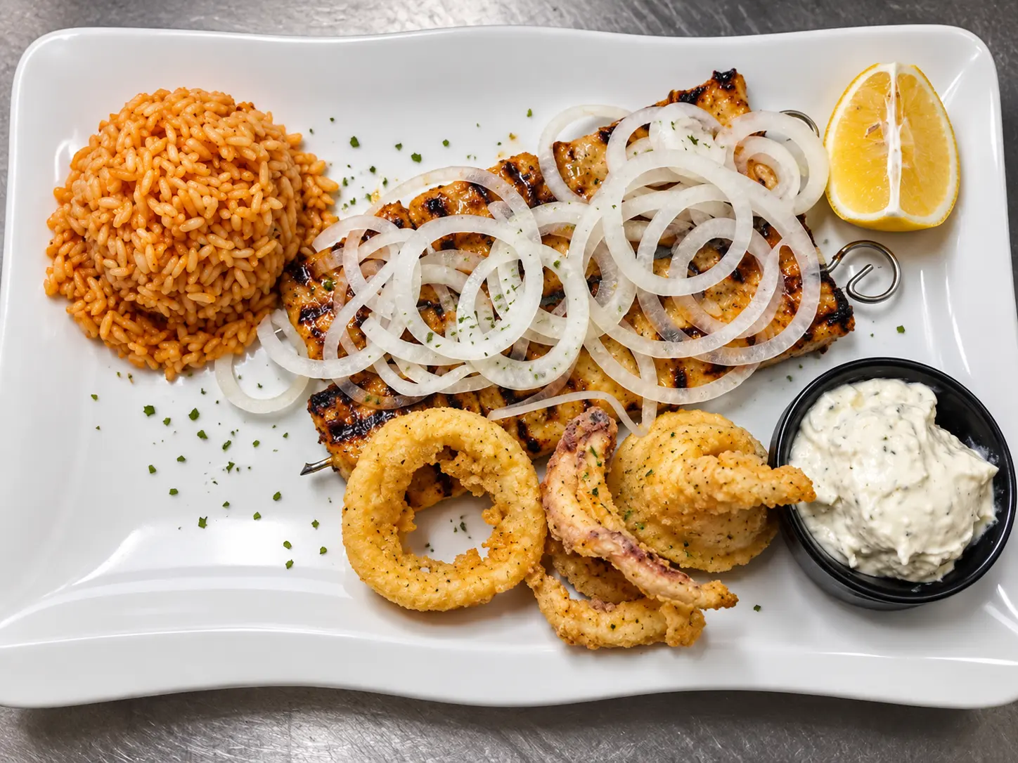 Souvlaki mit panierten Kalamari, Zwiebeln, Reis und Tzatziki.