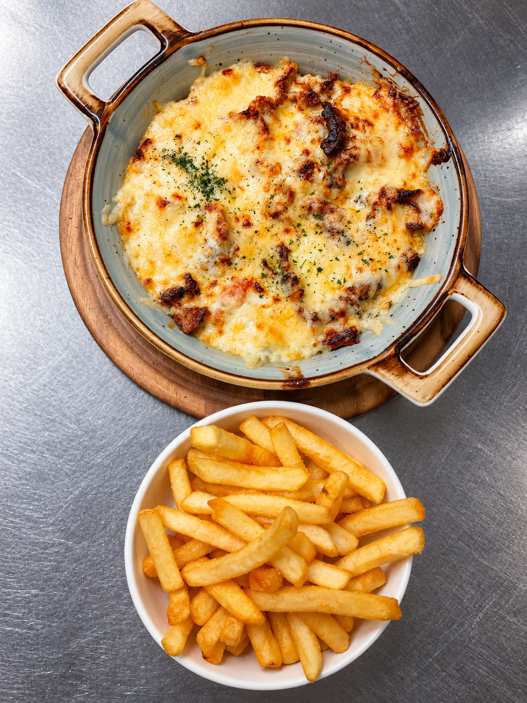 Überbackener Gyros-Auflauf mit Käse, Metaxasoße und Pommes.