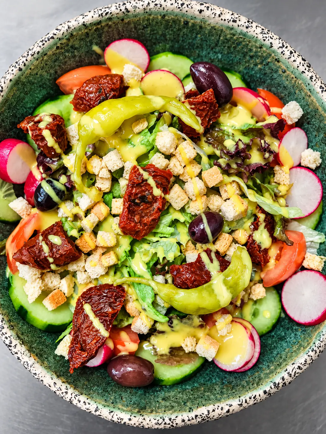 Gemischter Salat mit Oliven, Radieschen, Croutons und Peperoni.